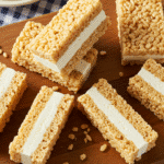 Homemade rice krispie treat ice cream sandwiches with vanilla ice cream on wooden serving board